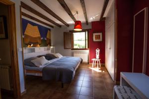 1 dormitorio con cama y pared roja en Casa Rural Andutza, en Ea