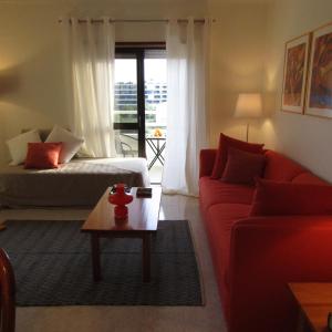 een woonkamer met een rode bank en een tafel bij Apartamento Turf in Alvor