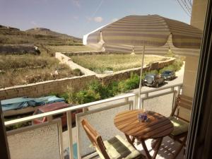 a table and chairs on a balcony with an umbrella at Coral Reef Flat 7 in Marsalforn