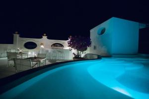 a swimming pool at night with a table and chairs at La Settima Luna Hotel in Canneto