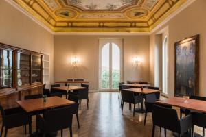 una sala da pranzo con tavoli, sedie e soffitto di Villa Pulejo a Messina