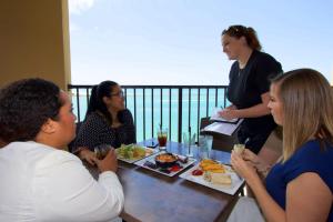 un grupo de personas sentadas alrededor de una mesa comiendo comida en Edge Hotel Clearwater Beach, en Clearwater Beach
