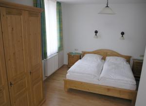 Schlafzimmer mit einem Bett mit weißer Bettwäsche und einem Schrank in der Unterkunft Landgasthof und Hotel Forchhammer in Pliening