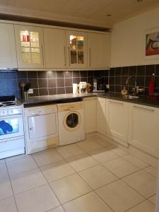 a kitchen with white cabinets and a washing machine at Glafsfjordens Accommodatie in Arvika