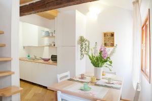 uma cozinha com paredes brancas e uma mesa com flores em Appartamento Calle dei Preti info at yourhomefromhomeinvenice-venicerentalapartments dot it em Veneza