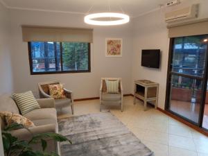 a living room with a couch and a tv at Flora Apartments in Puerto Iguazú
