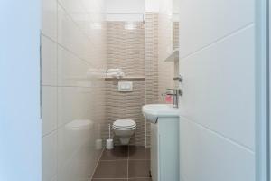 a white bathroom with a toilet and a sink at Apartments Biserka in Bol +34 photos