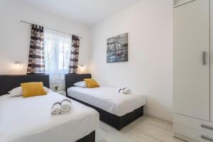 two beds in a small room with white walls at Apartments Biserka in Bol