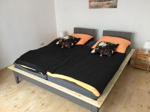 a large bed with black sheets and orange pillows at Ferienwohnung in Domnähe in Erfurt