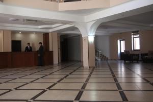 Türkistan的住宿－Hotel Khanaka，站在大楼柜台的身着西装的人