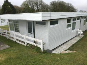 a white building with a white roof on a yard at Pine Song Chalet in Roch