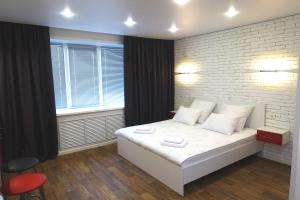 a bedroom with a white bed and a brick wall at KvartHaus on 40 Let Pobedy in Tolyatti