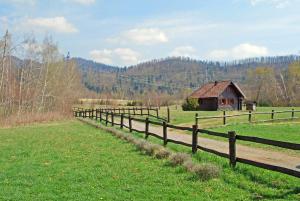 a wooden fence in front of a field with a barn at Chalets Zelena Vrata in Fužine