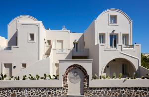 a large white building with a sign in front of it at Fileria Suites in Oia