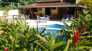 a house with a swimming pool and chairs and plants at Pousada Mareilha in Ilhabela