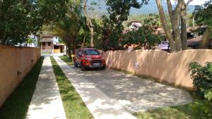 un coche rojo estacionado al lado de una entrada en Pousada Mareilha, en Ilhabela