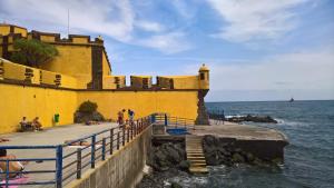 a yellow building next to the ocean with people on a pier at Apartments Madeira Old Town in Funchal