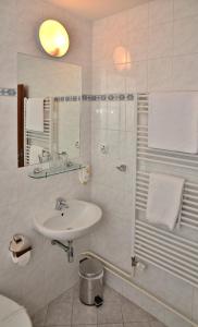 a white bathroom with a sink and a shower at Hotel Sonata in Hradec nad Moravici
