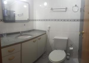 a bathroom with a toilet and a sink and a mirror at Apto Portal das Palmeiras in Ubatuba