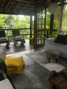 ein Wohnzimmer mit einem Sofa und Stühlen auf einer Veranda in der Unterkunft Casa Condominio Acquaville Ilhabela in Ilhabela