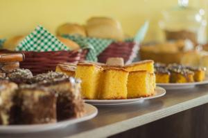 a table with plates of cakes and baskets of bread at Pousada Recanto Do Sussego in Olímpia