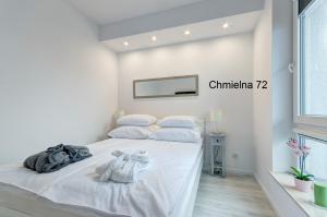 a white bedroom with a bed with white sheets and pillows at Twój Salon-Apartamenty Stare Miasto in Gdańsk