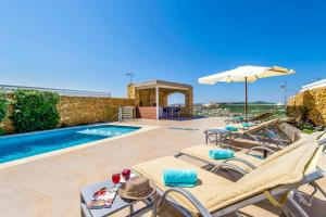 a villa with a swimming pool with chairs and an umbrella at Panorama in Xagħra