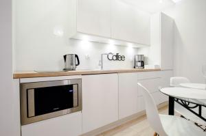 eine Küche mit weißen Schränken und einer Mikrowelle in der Unterkunft Apartament z basenem Polanki in Kołobrzeg