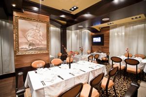 a dining room with white tables and chairs and a painting at Hotel Odissey Jaz in Budva