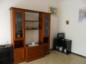 a living room with a wooden cabinet and a television at Parri Apartment in Follonica