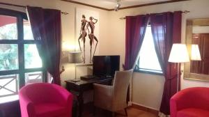 a room with two pink chairs and a tv and a desk at White Horse Residence in Tanji