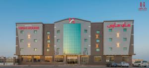 een hotelgebouw met auto's geparkeerd op een parkeerplaats bij High House in Sharurah