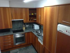 a small kitchen with wooden cabinets and a sink at Apartaments Vicus 1 con vistas a la Plaza Mayor de Vic in Vic