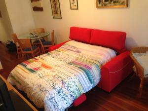 Dormitorio con cama roja y colcha colorida en Apartaments Vicus 1 con vistas a la Plaza Mayor de Vic en Vic