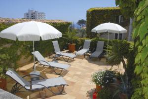 grupa krzeseł i parasoli na patio w obiekcie Petit Hotel Ses Rotges - Only Adults w Cala Ratjada