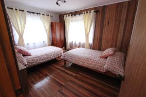 a bedroom with two beds and two windows at Chile Wild - Las Vertientes in Malalcahuello