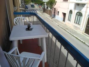 a white table and chairs on a balcony with a street at Casa da Figueira Da Foz in Figueira da Foz