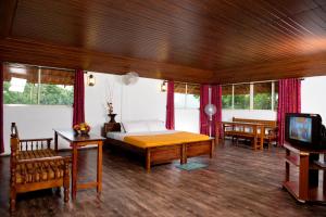 a bedroom with a bed and a tv and windows at Rock Haven Wayanad in Kalpetta