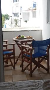 a table with two chairs and a plate of fruit on it at Very-Kokkos Pension 2 in Naxos Chora