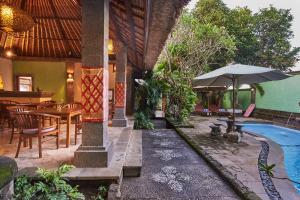 a house with a pool and a table and an umbrella at Ellies Hotel in Nusa Dua