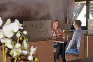 a man and woman sitting at a table in a restaurant at Hotel Die Kleine Blume in Erfweiler