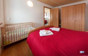 a bedroom with a bed with a red blanket at La Marmote Albergo Diffuso di Paluzza Testeons in Paluzza