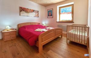 1 dormitorio con cama con manta roja y cuna en La Marmote Albergo Diffuso di Paluzza Testeons, en Paluzza 10 fotos más
