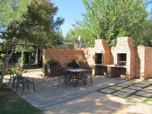 a patio with tables and chairs and a brick wall at Rusplek Guesthouse and Conference Centre in Bloemfontein