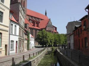 Un canal en una ciudad con edificios y una calle en Nikolaikirch-Hof, en Wismar