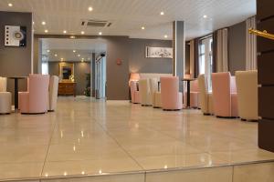 une salle d'attente avec des chaises roses et blanches dans l'établissement Hôtel Croix des Bretons - Lourdes Pyrénées, à Lourdes