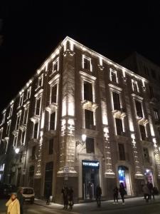 un grand bâtiment avec des lumières allumées la nuit dans l'établissement Il Gattopardo House, à Catane