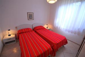 un letto con copriletto rosso a righe in una camera da letto di Villa Mary a Lignano Sabbiadoro