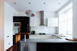 a kitchen with white cabinets and a black and white appliances at Apartment In The Strict City Centre in Łódź