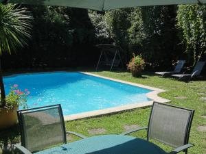 a swimming pool with two chairs and an umbrella at Hostellerie Sarrasine - M&acirc;con Est in Replonges